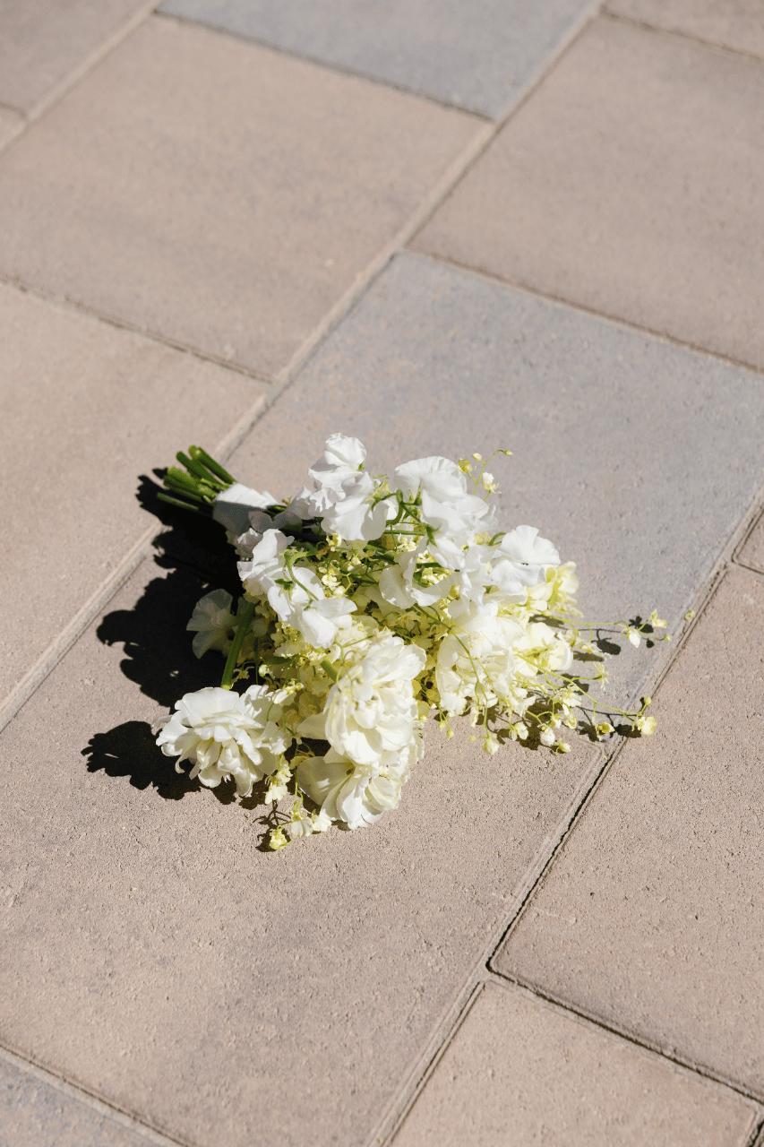 A textural white bouquet resting against warm desert stone.