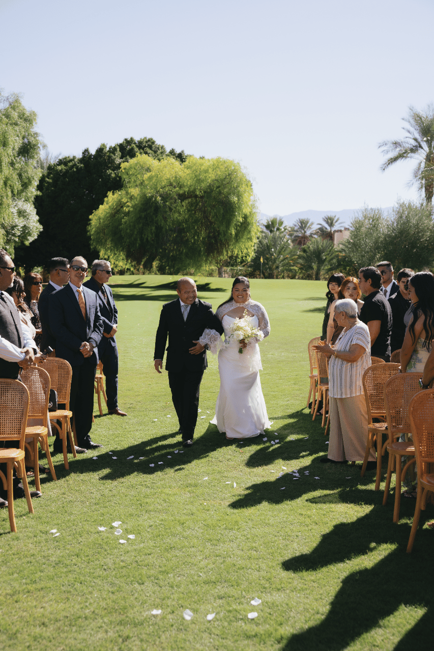 The bride’s entrance framed by palms and greenery.