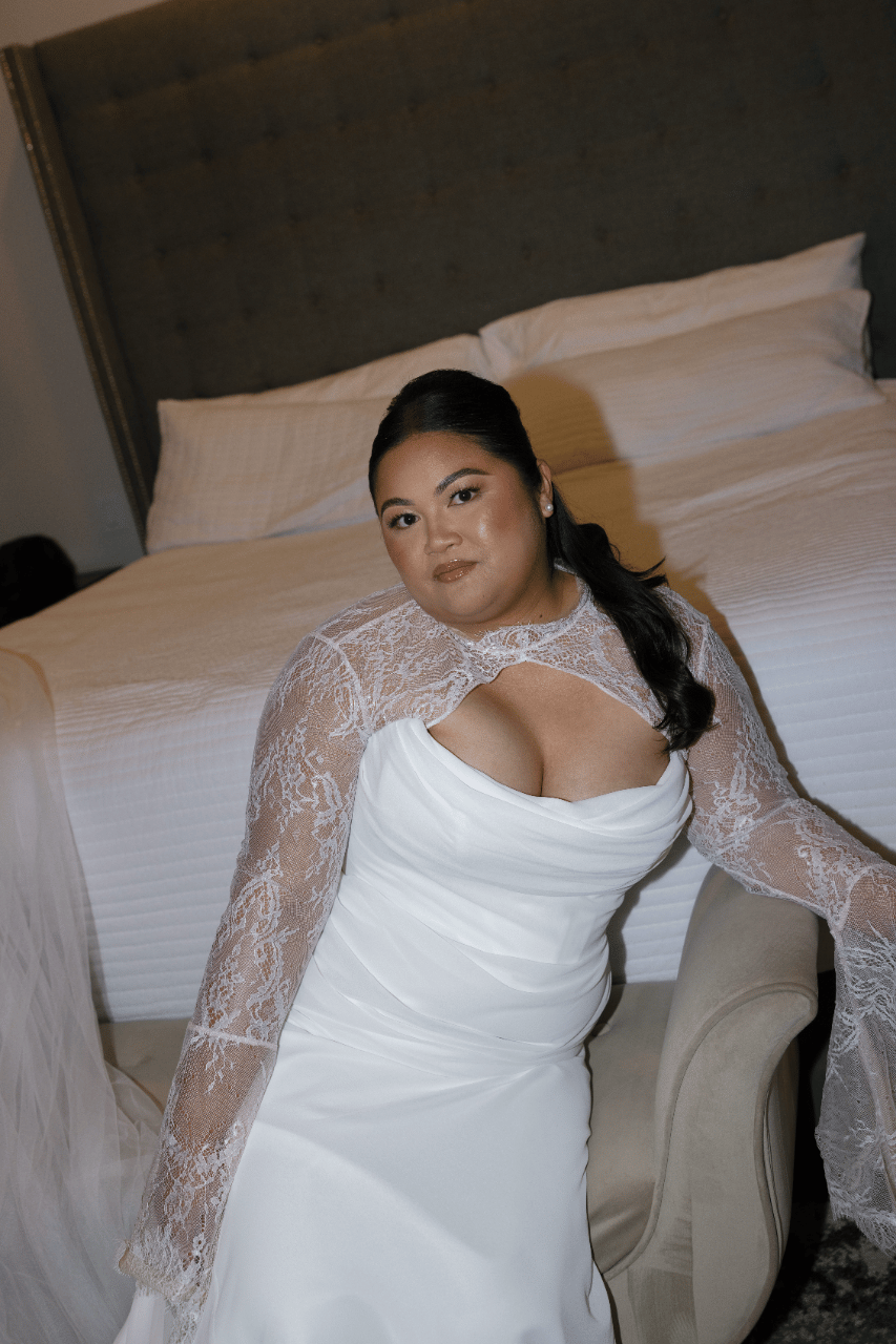 A quiet bridal portrait highlighting delicate lace sleeves and sculpted silhouette.
