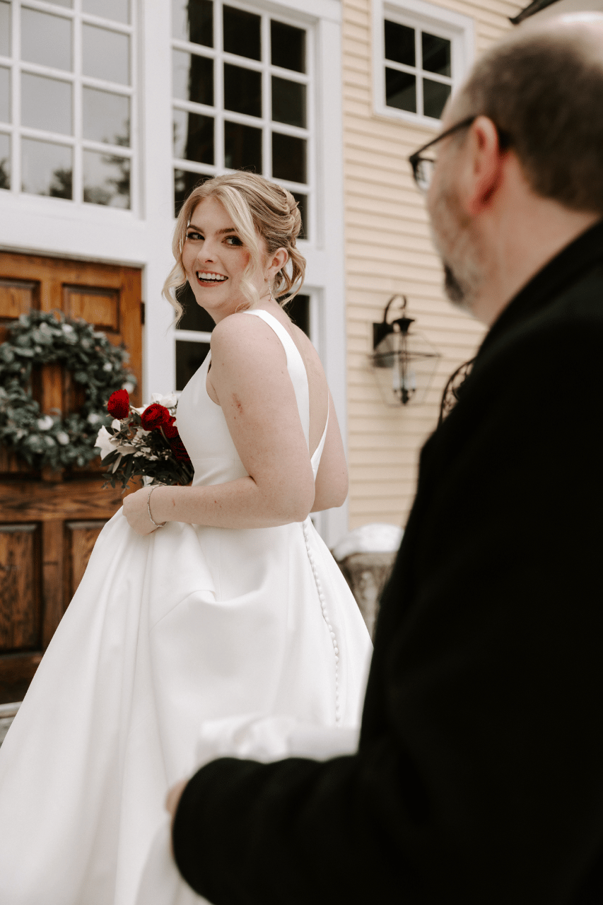 Bride stepping outside with her red and white bouquet for an emotional first look in the snow.
