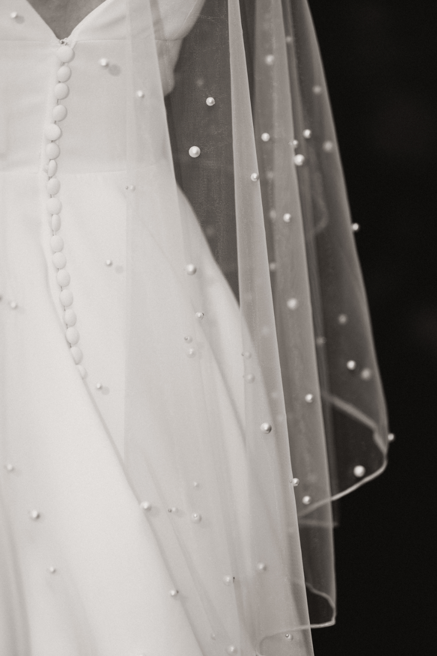 Pearl-detailed wedding gown and veil catching soft winter light.