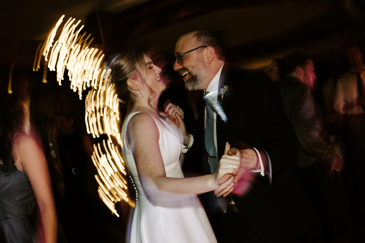 Romantic reception dancing under warm candlelight and twinkle lights.
